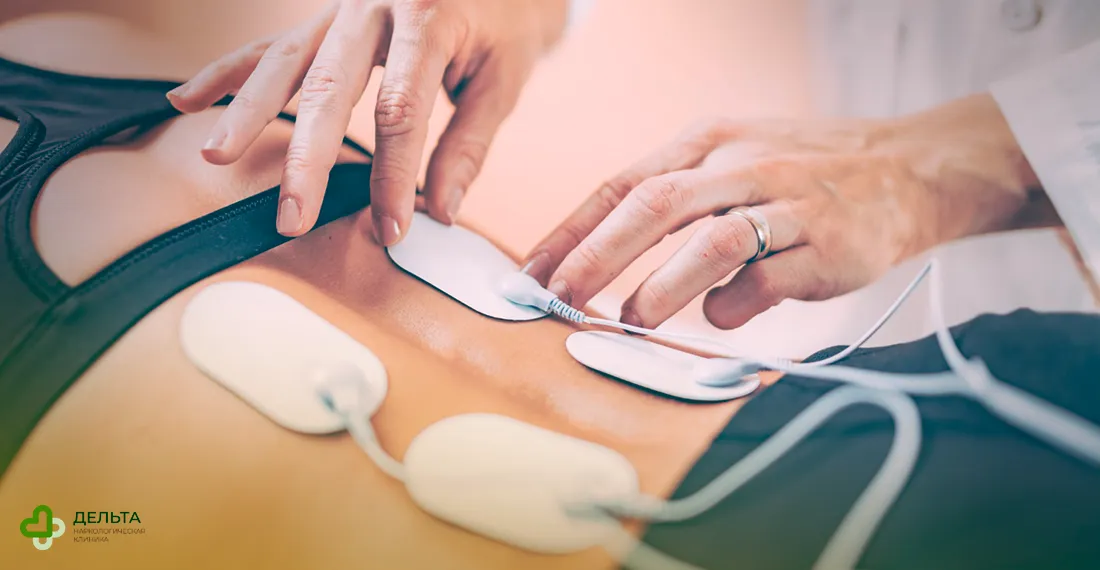 Врач прикрепляет электроды к спине пациентки